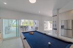 Indoor/outdoor entertainment room with pool table, dominos table, and TV.